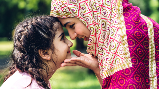 Young girl and mother smiling and touching foreheads together